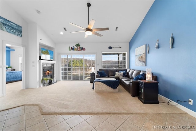 carpeted living room featuring tile patterned floors, visible vents, high vaulted ceiling, a glass covered fireplace, and ceiling fan