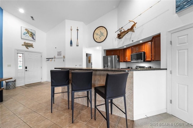 68 Lighthouse Rd Unit 344, Lake Ozark, MO 65049 - kitchen featuring stainless steel appliances, high vaulted ceiling, dark countertops, a breakfast bar area, and baseboards