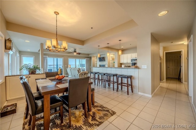 dining room with a raised ceiling, ceiling fan with notable chandelier, recessed lighting, light tile patterned floors, and baseboards