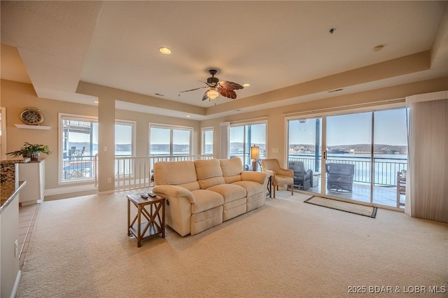 carpeted living room with a raised ceiling, recessed lighting, baseboards, and ceiling fan