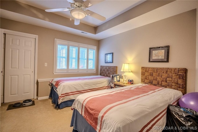 bedroom with a ceiling fan, baseboards, visible vents, carpet floors, and a tray ceiling