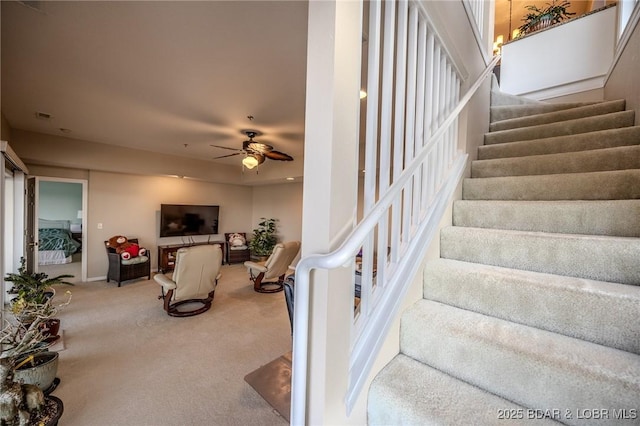 staircase featuring baseboards, visible vents, a ceiling fan, and carpet