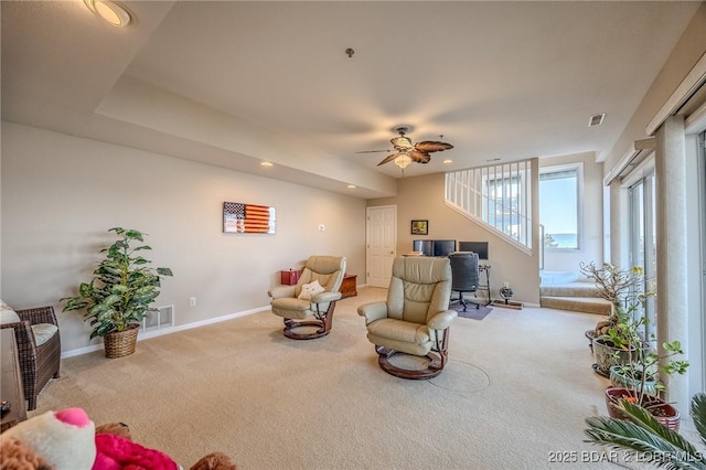 living area featuring baseboards, visible vents, a ceiling fan, and carpet