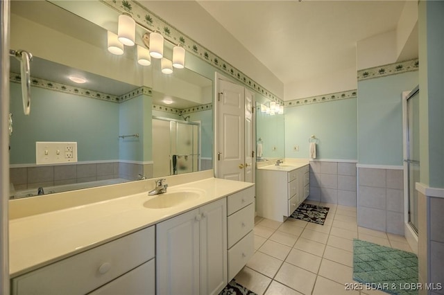 bathroom with two vanities, a stall shower, a sink, tile patterned flooring, and tile walls