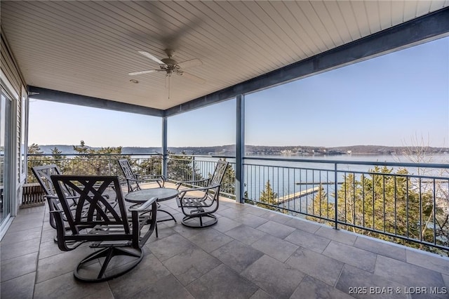 exterior space featuring a balcony, a ceiling fan, and a water view