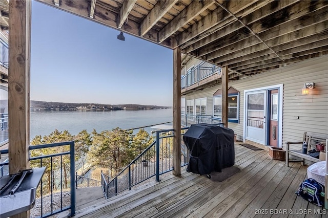 wooden terrace featuring area for grilling and a water view