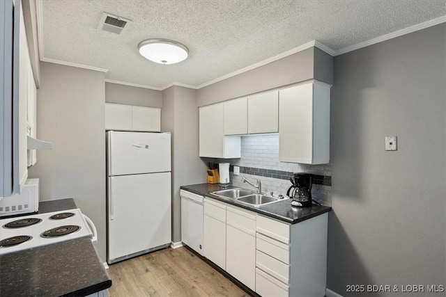 kitchen featuring dark countertops, visible vents, light wood-type flooring, white appliances, and a sink