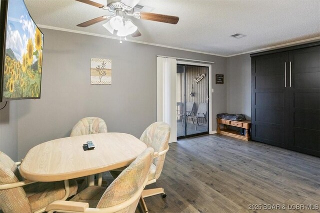 dining room with a textured ceiling, ceiling fan, wood finished floors, and ornamental molding