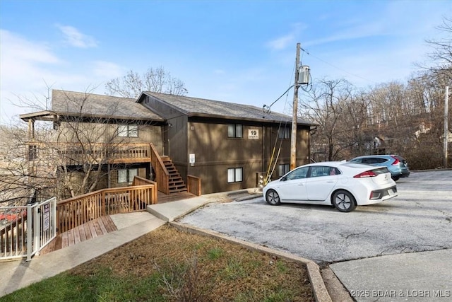 view of front of property featuring stairway and a shingled roof