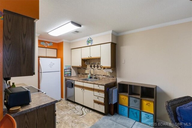 kitchen featuring visible vents, dishwasher, decorative backsplash, freestanding refrigerator, and a sink