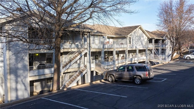 view of property with stairs and uncovered parking