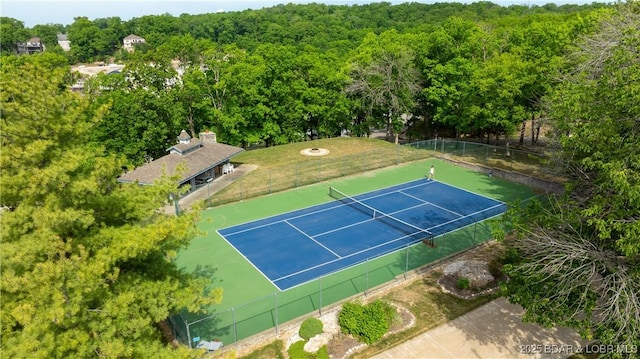 view of sport court with a wooded view and fence