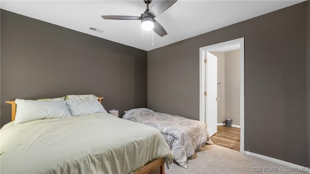 bedroom with visible vents, baseboards, light colored carpet, and a ceiling fan