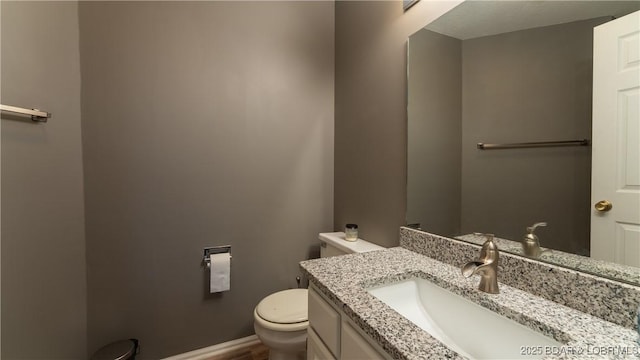 bathroom featuring toilet, vanity, and baseboards