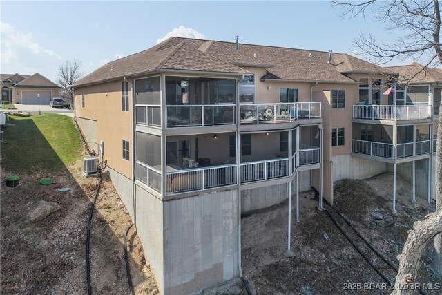 145 Bella Terra Ct, Sunrise Beach, MO 65079 - back of house with roof with shingles, a sunroom, central AC, stucco siding, and a lawn