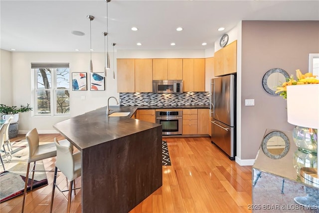 145 Bella Terra Ct, Sunrise Beach, MO 65079 - kitchen featuring dark countertops, light brown cabinets, a peninsula, a kitchen breakfast bar, and stainless steel appliances