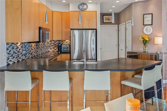 145 Bella Terra Ct, Sunrise Beach, MO 65079 - kitchen with dark countertops, backsplash, a peninsula, brown cabinetry, and stainless steel fridge