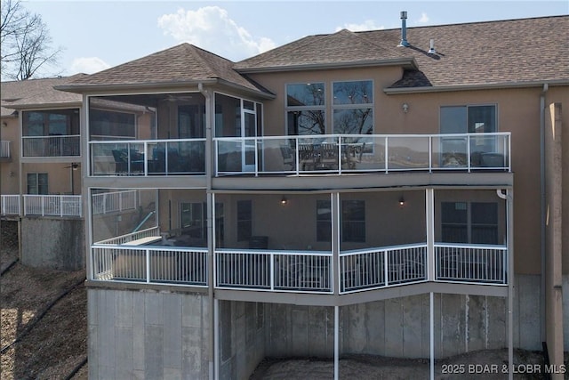 145 Bella Terra Ct, Sunrise Beach, MO 65079 - back of property with stucco siding, a shingled roof, a balcony, and a sunroom