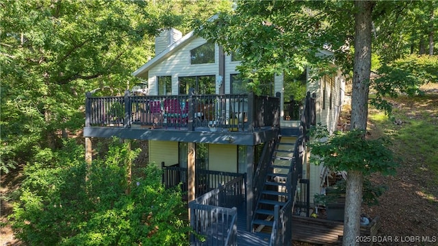 rear view of house featuring a wooden deck, a chimney, and stairway