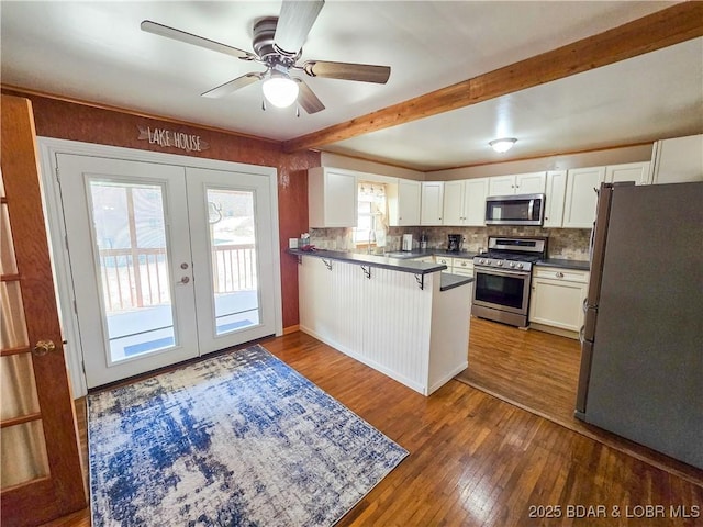 kitchen featuring wood-type flooring, a peninsula, appliances with stainless steel finishes, and white cabinets