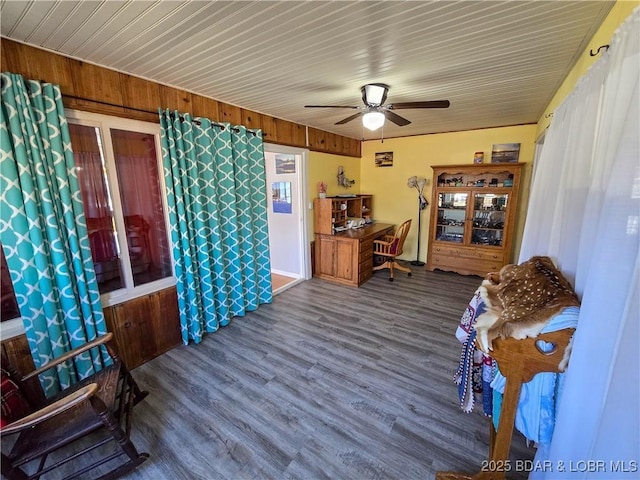 interior space with ceiling fan, wood finished floors, and wooden walls