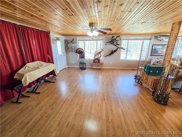 living area featuring light wood-style floors, baseboards, ceiling fan, and a healthy amount of sunlight