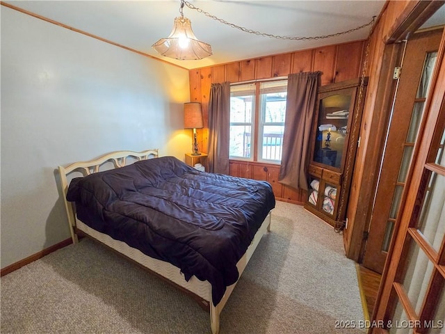 bedroom with light colored carpet, wood walls, and baseboards