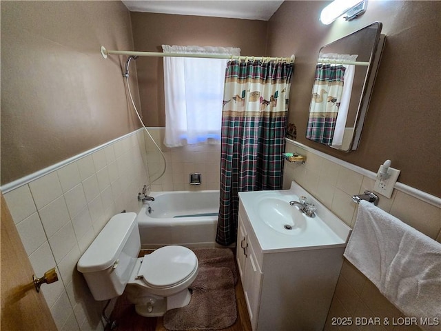 full bath with vanity, toilet, shower / bathtub combination with curtain, a wainscoted wall, and tile walls