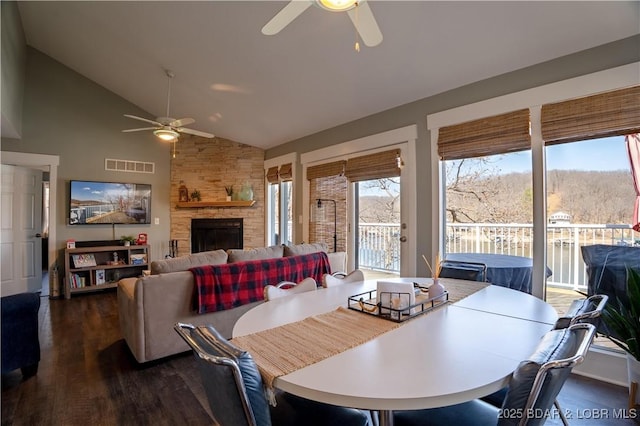 2813 Great Lake View Dr, Gravois Mills, MO 65037 - dining area with ceiling fan, dark wood-style floors, a stone fireplace, and high vaulted ceiling