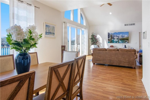 dining room with high vaulted ceiling, visible vents, light wood finished floors, and ceiling fan