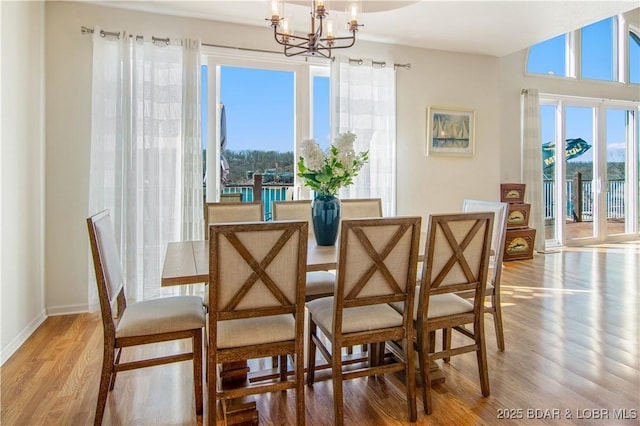 dining space featuring a notable chandelier, plenty of natural light, baseboards, and light wood-style floors
