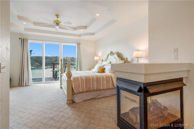 bedroom featuring a tray ceiling, recessed lighting, access to exterior, and light colored carpet