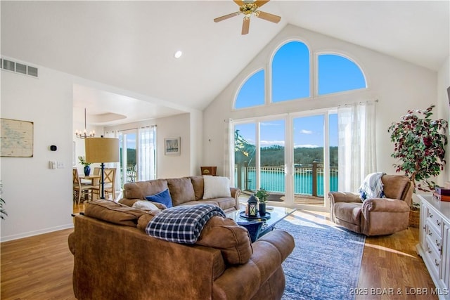 living room with visible vents, ceiling fan with notable chandelier, plenty of natural light, and wood finished floors