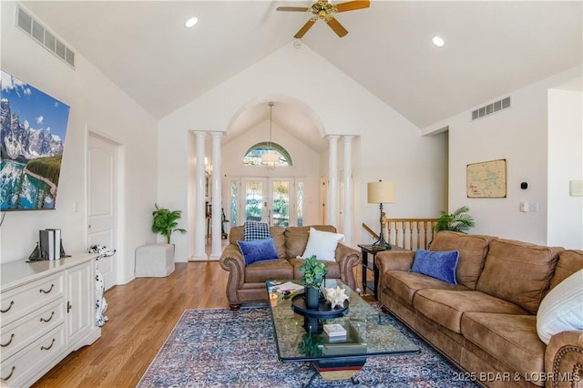 living room featuring light wood-style flooring, decorative columns, a ceiling fan, and visible vents
