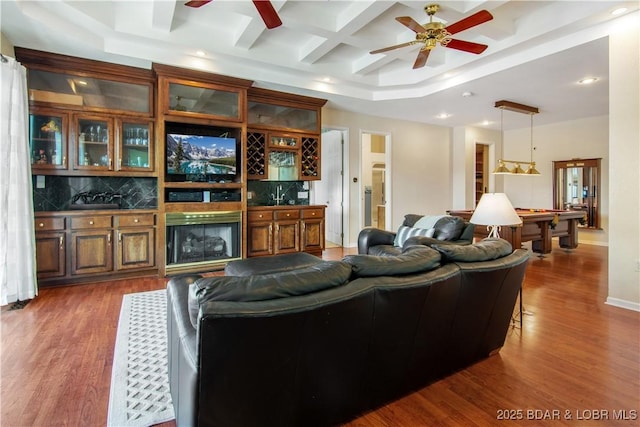 living area featuring a large fireplace, dark wood-style floors, coffered ceiling, billiards, and a ceiling fan