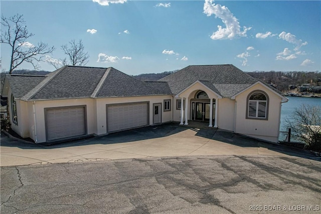 view of front of house with aphalt driveway, a garage, roof with shingles, and stucco siding