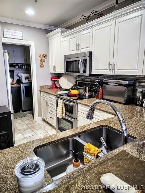 201 Marina Residence Dr Unit 3C, Camdenton, MO 65020 - kitchen with stainless steel appliances, crown molding, washer / clothes dryer, and white cabinetry