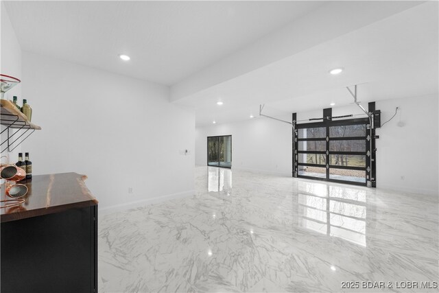 unfurnished room with healthy amount of natural light, recessed lighting, marble finish floors, and baseboards