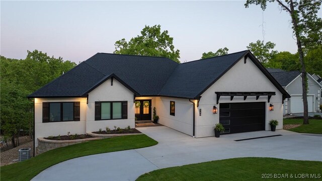 modern inspired farmhouse with driveway, a garage, stucco siding, and a front yard