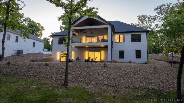 rear view of property featuring a balcony, stucco siding, and cooling unit