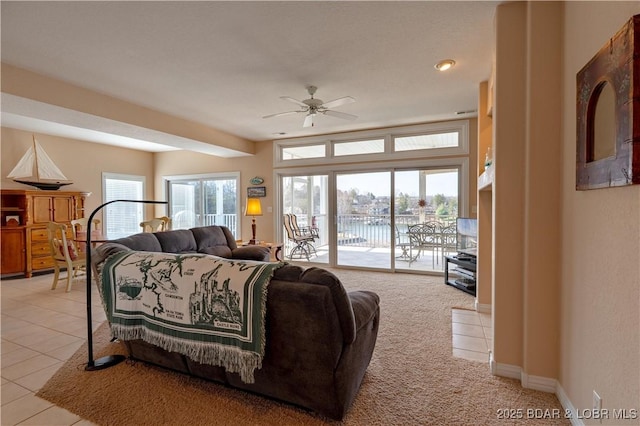 living area with light tile patterned floors, baseboards, and a ceiling fan