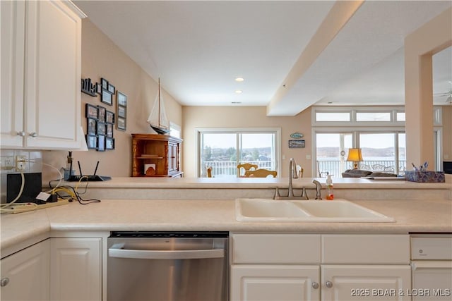 kitchen with white cabinets, dishwasher, light countertops, and a sink