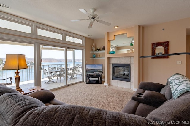 carpeted living room with visible vents, ceiling fan, and a tile fireplace
