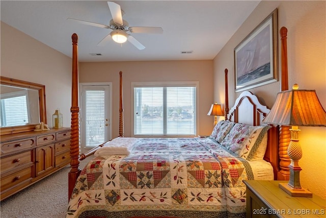 carpeted bedroom with access to exterior, visible vents, and a ceiling fan