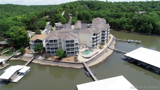 birds eye view of property featuring a water view and a wooded view