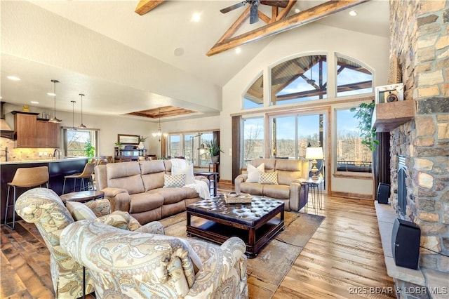 living room featuring ceiling fan, beamed ceiling, a fireplace, high vaulted ceiling, and wood finished floors