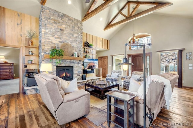 living room featuring high vaulted ceiling, wood finished floors, beam ceiling, a fireplace, and a chandelier