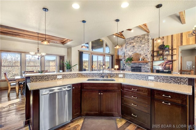 kitchen featuring dishwasher, a sink, open floor plan, a fireplace, and a chandelier