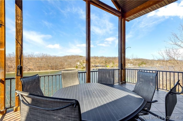 deck with outdoor dining space and a water view