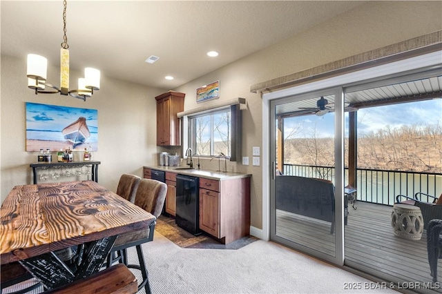 kitchen featuring a chandelier, light colored carpet, light countertops, a sink, and pendant lighting